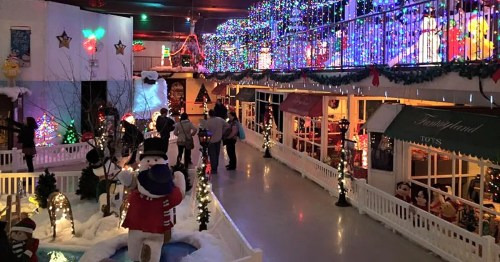 A festive indoor scene filled with colorful holiday lights, decorations, and visitors enjoying the winter display.