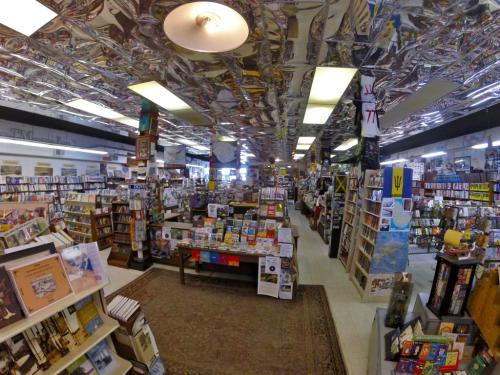 A spacious bookstore filled with shelves of books and CDs, featuring a unique, patterned ceiling.