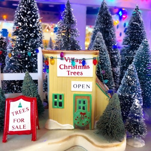 A charming miniature shop labeled "Vintage Christmas Trees" with colorful lights, surrounded by snowy trees.