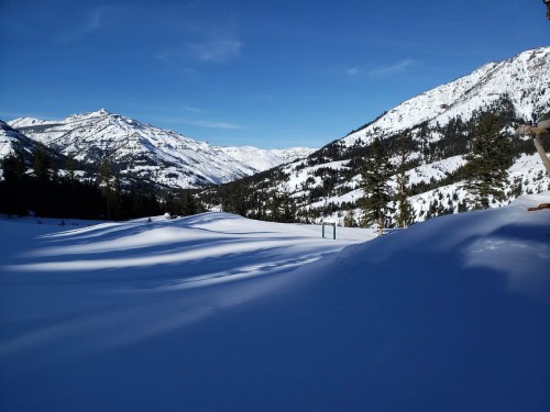 A snowy mountain landscape with tall peaks and a clear blue sky, showcasing a serene winter scene.