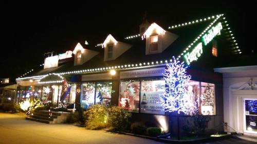 A festive building decorated with colorful Christmas lights and a glowing "Happy Holidays" sign at night.