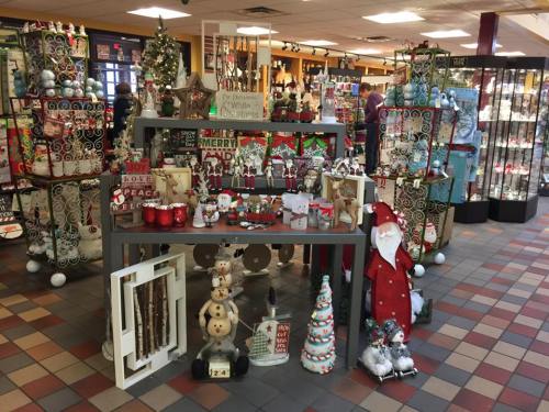 A festive display of holiday decorations, including ornaments, signs, and figurines, in a cheerful store setting.