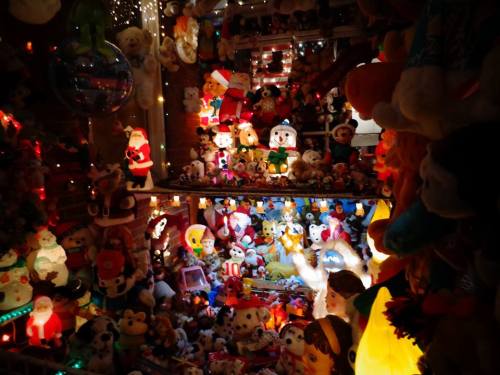 A colorful display of various stuffed animals and holiday decorations, illuminated with festive lights.