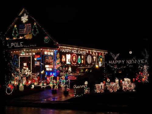 A house decorated with colorful holiday lights and festive decorations, celebrating the season with "Happy Holidays" and "Happy New Year."