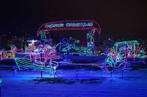 Colorful holiday lights display featuring a "Camping Christmas" theme with festive decorations and characters.