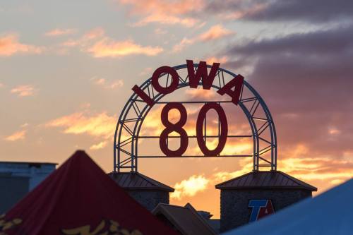 Sign for Iowa 80, the world's largest truck stop, against a colorful sunset sky.