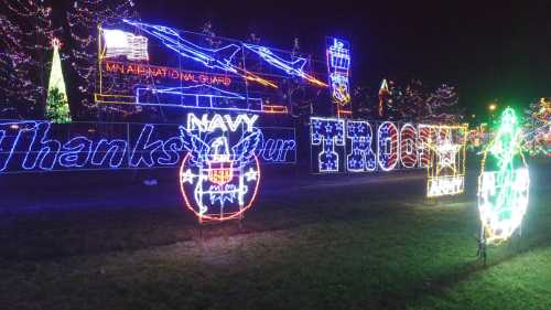 Colorful holiday lights display featuring "Thanks Our Troops" and military-themed decorations.