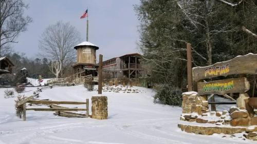 A snowy landscape featuring a rustic building, a flagpole, and a sign for "Ponderosa Mountain."