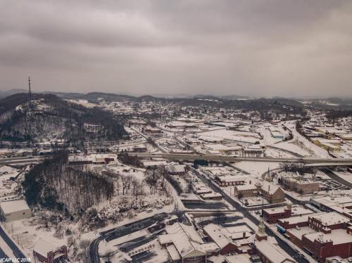 Aerial view of a snowy town with hills in the background and a highway running through the landscape.