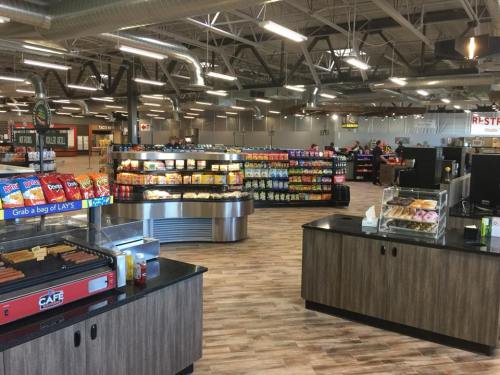 Interior of a convenience store featuring snack aisles, a hot dog station, and a bakery display. Bright and spacious layout.