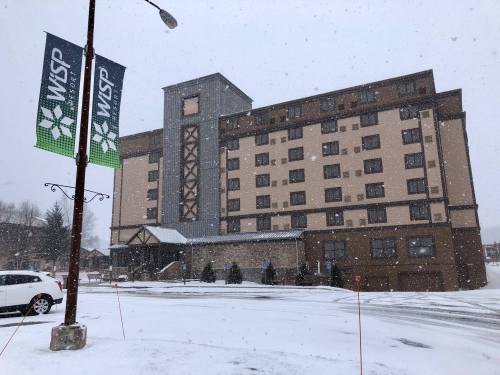 A hotel building in a snowy landscape, with banners and a parked car in front. Snowflakes are falling.