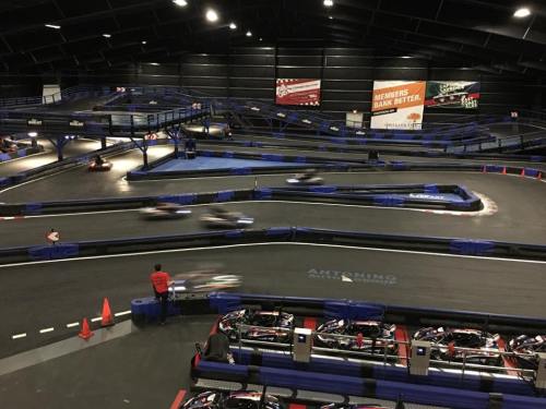 Indoor go-kart track with multiple winding lanes and karts racing. Red cones mark the track boundaries.