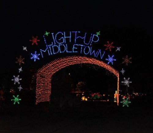 A festive archway illuminated with colorful lights reading "Light Up Middletown," surrounded by snowflake designs.
