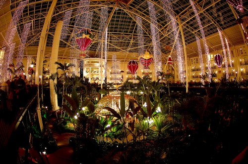A beautifully decorated indoor garden with colorful lights and large ornaments hanging from the ceiling.