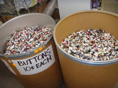 Two large barrels filled with a colorful assortment of buttons, labeled "BUTTONS 10¢ EACH."
