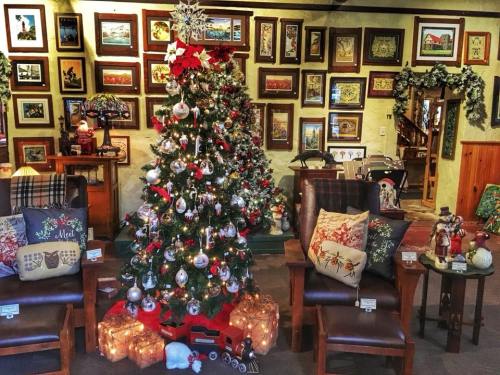 A cozy room decorated for Christmas, featuring a beautifully adorned tree and framed artwork on the walls.