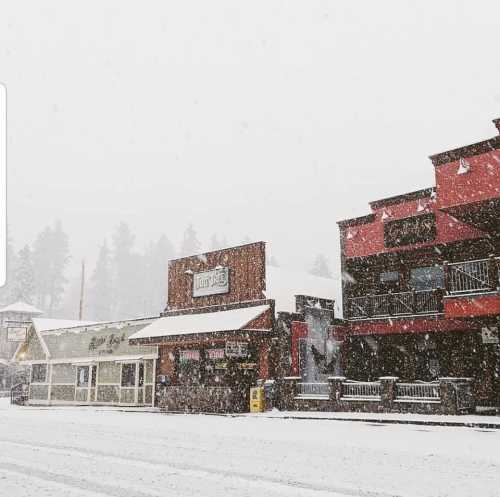 Snowy street scene with shops and buildings, blanketed in white, creating a cozy winter atmosphere.