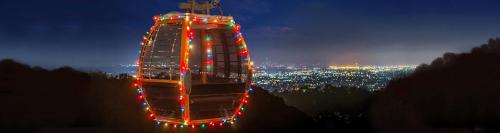 A brightly lit gondola at night, overlooking a city skyline adorned with twinkling lights.