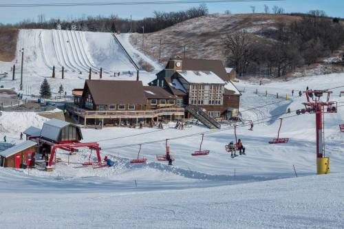 A snowy ski resort with a lodge, ski lifts, and slopes in the background, bustling with winter activity.