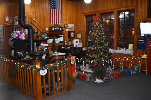 A festive office decorated for the holidays, featuring a Christmas tree, gifts, and seasonal decorations.