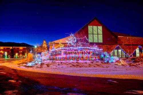 A brightly lit resort entrance decorated with colorful lights against a twilight sky and snowy ground.