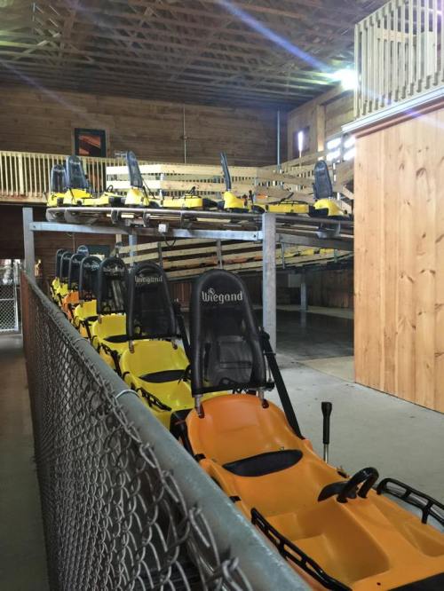A row of yellow go-karts lined up in a wooden building with a loft area above.