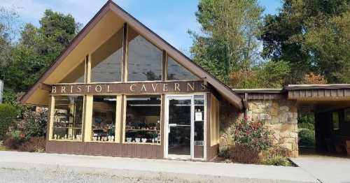 Exterior of Bristol Caverns building with large windows, stone accents, and surrounding greenery on a sunny day.