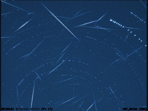 A starry night sky filled with streaks of light, representing meteor trails and celestial movement.