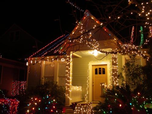 A cozy house decorated with colorful Christmas lights, glowing warmly against the night sky.