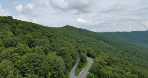 A winding road through lush green mountains under a partly cloudy sky.