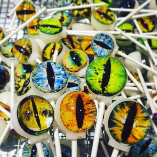 A collection of colorful lollipops designed to look like reptilian eyes, featuring vibrant greens, blues, and oranges.