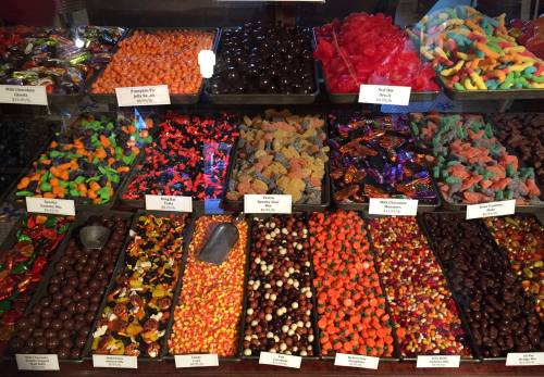 A colorful display of various candies, including gummies, chocolates, and seasonal treats in a shop window.