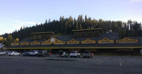 A rustic building with "Silver Dollar" signage, featuring a casino, motel, and restaurant, surrounded by trees.
