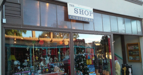 A storefront labeled "The Shop Christmas" with festive decorations and a Christmas tree visible inside.