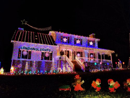 A brightly lit house decorated with colorful Christmas lights, featuring festive characters in the yard.