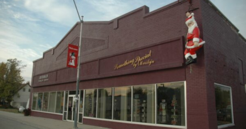 A festive storefront with large windows, featuring a Santa decoration on the side and holiday banners.
