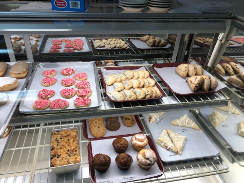 A display case filled with various baked goods, including cookies, pastries, and bars, arranged on trays.