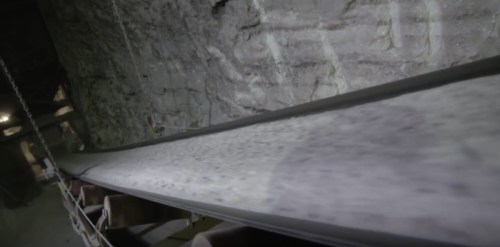 Conveyor belt transporting material through a dimly lit underground mine.