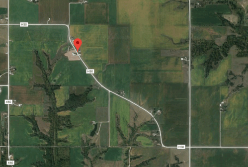 Aerial view of a rural area with fields and roads, marked by a red pin indicating a specific location.