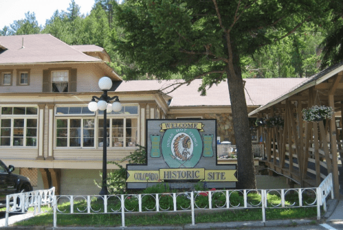 Sign welcoming visitors to the Columbine Historic Site, with a rustic building and trees in the background.