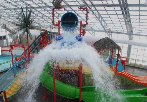 A colorful water park with slides and a large water feature pouring down from above.