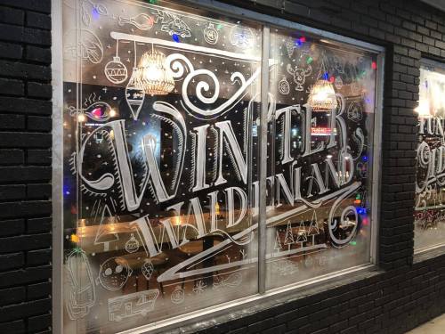 Window display featuring decorative lettering that reads "Winter Walden" with festive designs and lights.