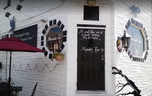 A white building with a black door and decorative windows, featuring a sign that reads "Annabel Lee Tavern."