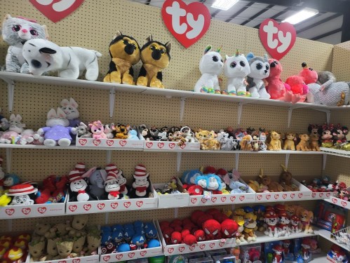 A colorful display of various Ty plush toys arranged on shelves, featuring animals and popular characters.