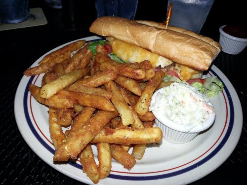 A plate featuring a sandwich with cheese and lettuce, accompanied by a generous serving of golden fries and coleslaw.