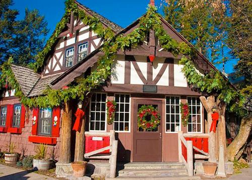A charming, festive building adorned with greenery and red decorations, set against a clear blue sky.