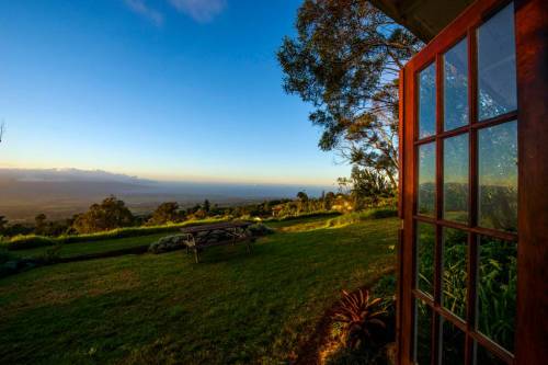A scenic view from an open door, showcasing a lush green landscape and a clear blue sky.