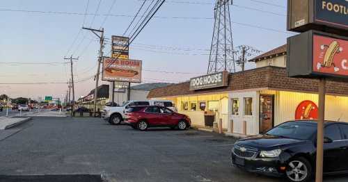 A street view of a restaurant called "Dog House" with parked cars and a clear evening sky.