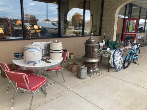 A display of vintage items outside a store, including furniture, a bicycle, and various decorative objects.