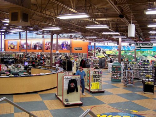 A spacious retail store interior with displays, a checkout counter, and signs for restrooms.